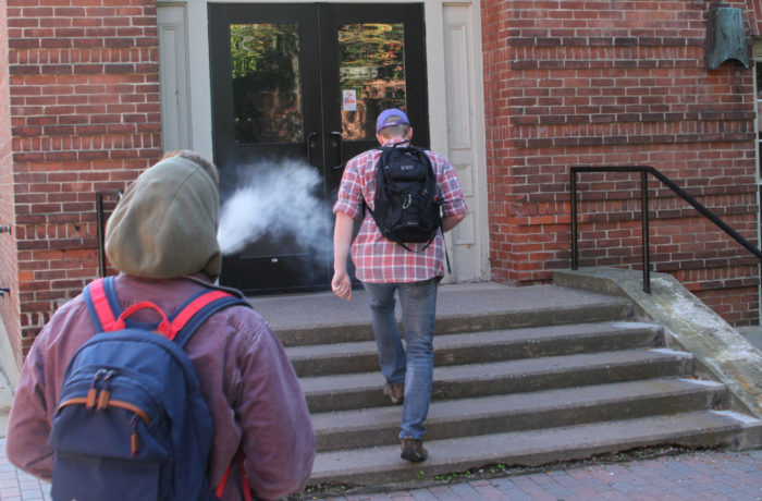 Student exhales a cloud of vapor from an e-cig as he walks into Jeanmarie hall on Wednesday afternoon. (Garrett Finn)